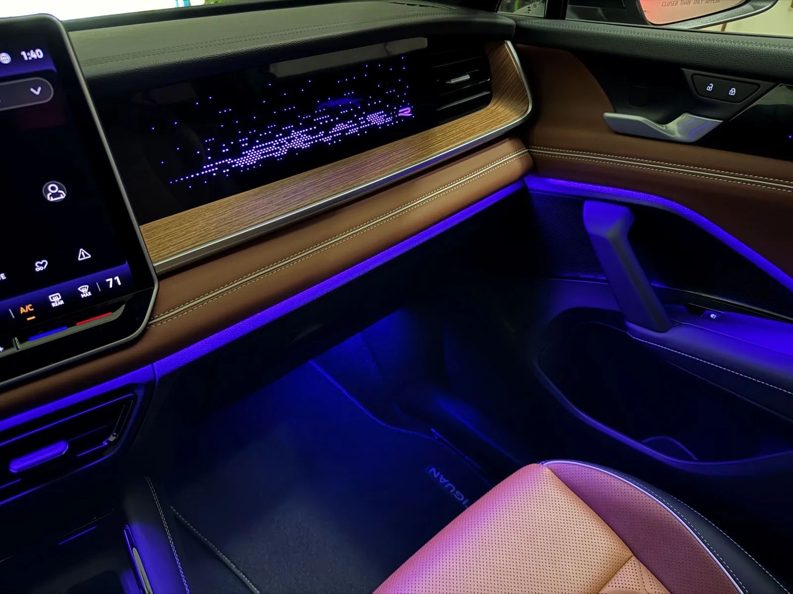 Une teinte bleue accentue le sol de l'habitacle intérieur du Volkswagen Tiguan SEL R-Line, contrastant joliment avec les sièges en cuir brun ambré.