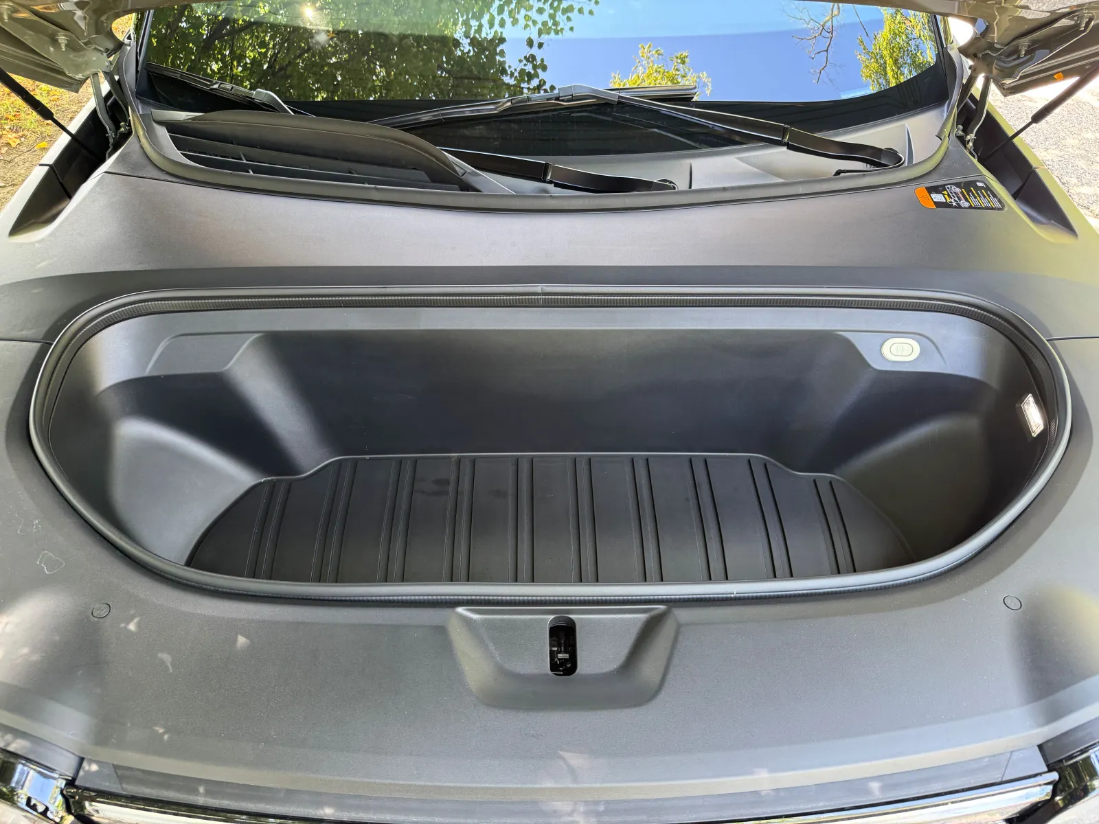Le coffre ouvert d'un véhicule est illustré. Un coffre, également connu sous le nom de coffre avant, est courant dans les véhicules électriques